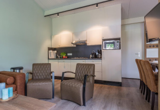 Moderne woonkamer en keuken in Residence De Eese 3 lodge in Nederland met comfortabele zitplaatsen.