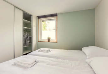Helles Schlafzimmer mit zwei Betten in der Residence De Eese 3 Lodge in den Niederlanden, offener Kleiderschrank.