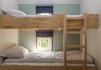 Stockbetten aus Holz mit Leiter und Fenstern in einem hellen Raum der Residence De Eese 3, Niederlande.