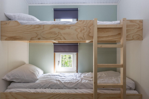 Houten stapelbedden met ladder en ramen in een lichte kamer van Residence De Eese 3, Nederland.
