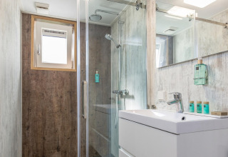 Moderne badkamer met douchecabine, raam en wastafel in Residence De Eese 3 lodge in Nederland, licht en netjes.