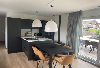 Moderne køkken- og spisestue i en lodge ved Recreation Park Idskenhuizen, Nederlandene, med store vinduer.