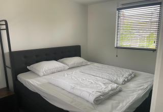 Schlafzimmer in Recreation Park Idskenhuizen 11, Niederlande, mit Doppelbett und Fenster.
