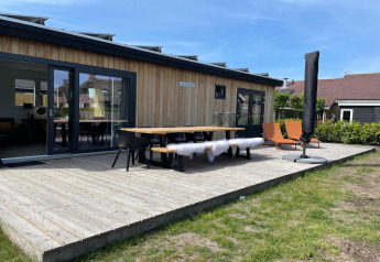 Udendørs terrasse ved lodge i Recreation Park «Idskenhuizen 11», med borde, stole og liggestole.
