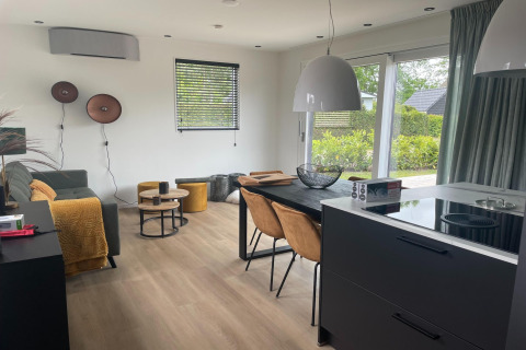 Modernes Wohnzimmer und Küche in einer Lodge im Recreation Park Idskenhuizen 11, Niederlande, mit großen Fenstern.