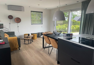 Modernes Wohnzimmer und Küche in einer Lodge im Recreation Park Idskenhuizen 11, Niederlande, mit großen Fenstern.