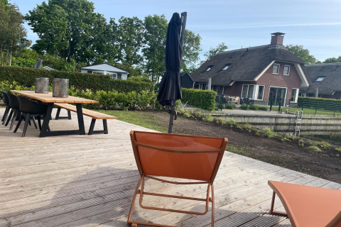 Udendørs terrasse ved Recreation Park Idskenhuizen 11 i Holland med borde, stole og udsigt til hytter.