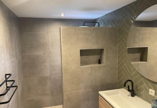 Modernes Badezimmer mit grauen Fliesen, rundem Spiegel und schwarzem Wasserhahn, Recreation Park Idskenhuizen 11.