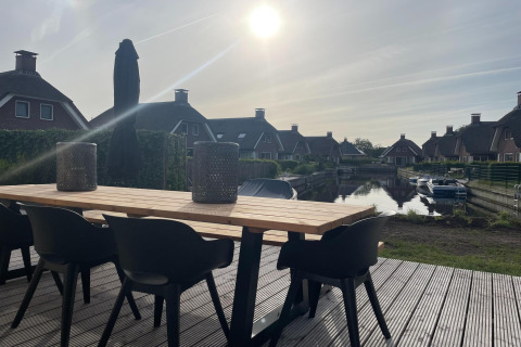 Terrasse im Erholungspark Idskenhuizen 11, Niederlande, mit modernen Möbeln und Blick auf den Kanal.