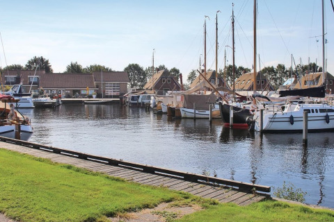 Både og moderne hytter ved en rolig havn i Recreation Park Idskenhuizen 11, Holland, på en solskinsdag.
