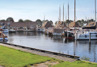 Boote an einem ruhigen Hafen mit modernen Hütten im Recreation Park Idskenhuizen 11 in den Niederlanden.