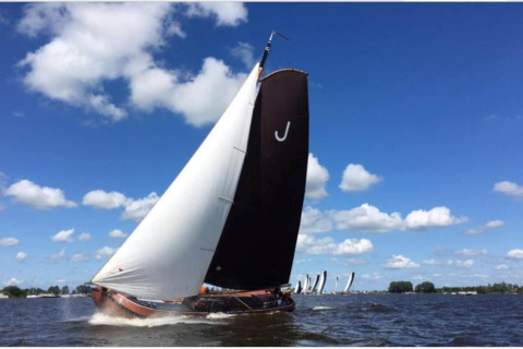 Segelboot nimmt an einer Regatta unter blauem Himmel im Recreation Park Idskenhuizen, Niederlande, teil.