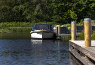 Boot an einem Holzsteg im Recreation Park Idskenhuizen in den Niederlanden, umgeben von grüner Natur.