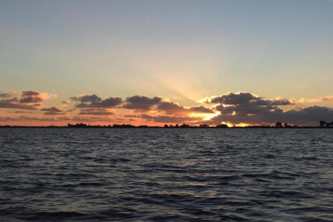 Solnedgang over vandet ved Recreation Park Idskenhuizen 11, Nederlandene med skyer og bløde farver.