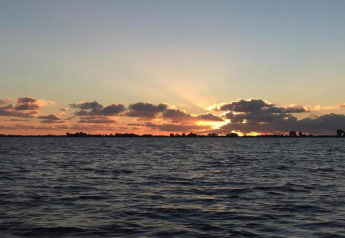 Atardecer sobre el agua en Recreation Park Idskenhuizen 11, Países Bajos, con nubes y cielo colorido.