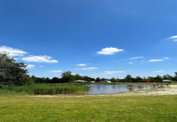 Vista de un lago pequeño con césped y personas, en el Recreation Park Idskenhuizen, Países Bajos.