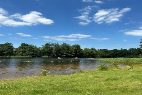 Giornata soleggiata al lago presso Recreation Park Idskenhuizen 11, Paesi Bassi, con cielo blu e alberi verdi.