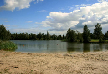 Strand mit Blick auf einen See im Erholungspark Idskenhuizen 11, umgeben von Bäumen und Himmel