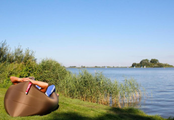 Persona relajándose en una silla inflable junto al lago en Recreation Park Idskenhuizen 11, Países Bajos.