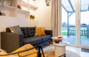 Hyggelig stue i Chalet «Imke» i Holland med moderne sofa, sofabord og udsigt til grønne marker.