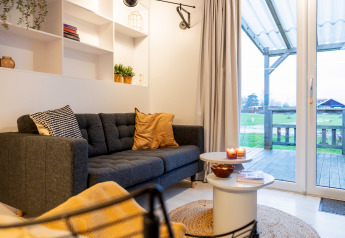 Hyggelig stue i Chalet «Imke» i Holland med moderne sofa, sofabord og udsigt til grønne marker.
