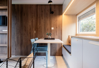 Moderne spiseplads i Chalet Imke i Nederlandene med træpaneler, vinduesbænk og stilfuldt møblement.