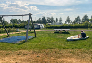 Enfants jouant près du Chalet « Imke » aux Pays-Bas avec balançoires, table de ping-pong et caravanes proches.