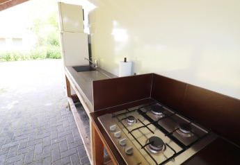 Outdoor kitchen with gas stove, sink, and fridge beside a teepee tent in the Netherlands, bright space.