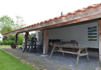 Covered outdoor kitchen and wooden picnic table near the teepee tents 'Kreas' and 'Smuk' in Holland.