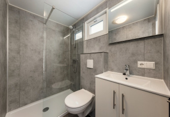 Moderne badkamer in Hunzepark 13 in Nederland met douche, toilet, wastafel en spiegelkast.