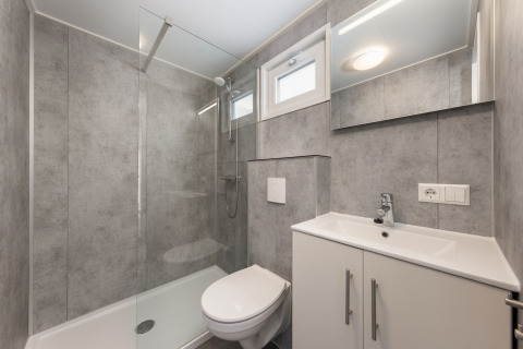 Moderne badeværelse i Hunzepark 13 i Holland med brusekabine, toilet og vask med skab.
