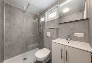 Moderne badeværelse i Hunzepark 13 i Holland med brusekabine, toilet og vask med skab.