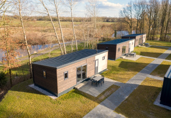 Luchtfoto van moderne lodges in Hunzepark 13 in Nederland, omgeven door natuur en water.
