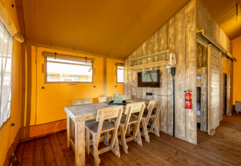 Interieur van safaritent Hunzepark 15 in Nederland met houten eettafel en sfeervolle inrichting.
