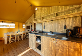Keuken en eetgedeelte van een safaritent op Hunzepark 15 in Nederland met houten inrichting.