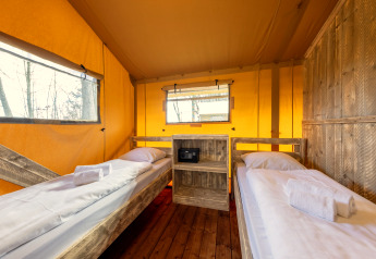 Interieur van safaritent 'Hunzepark 15' in Nederland met twee eenpersoonsbedden en houten vloer.