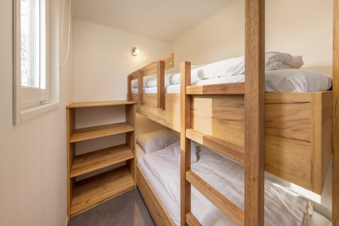 Værelse med køjesenge i træ og stort vindue på Hunzepark 13 lodge, Holland, lyst og hyggeligt.