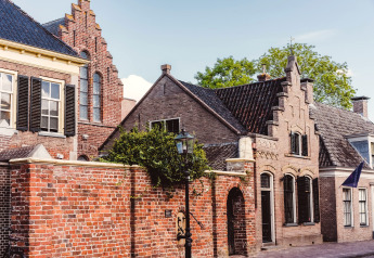 Traditionele Nederlandse bakstenen huizen met trapgevels en zonnige straat bij Hunzepark 15, Nederland.