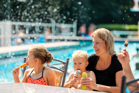 A family enjoys ice cream by a swimming pool at the Hunzepark 15 safari tent in the Netherlands.