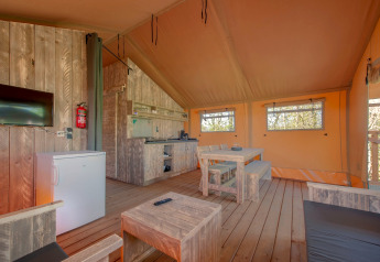 Interiør af et safari telt i Holiday Park «Hunzedal 17», Nederlandene, med træmøbler og tekøkken.
