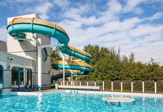 Udendørs swimmingpool med vandrutsjebane ved ferieparken Hunzedal 17 i Holland på en solrig dag.