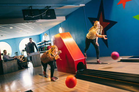 To personer bowler indendørs i farverig bane med stjerner på væggen i Holiday Park Hunzedal 17, Holland.