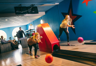 Twee mensen bowlen op een kleurrijke binnenbaan met sterrenwand in Holiday Park Hunzedal 17, Nederland.