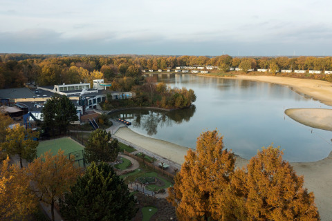 Udsigt over søen og ferieparken Holiday Park «Hunzedal 17» omgivet af efterårstræer i Holland.