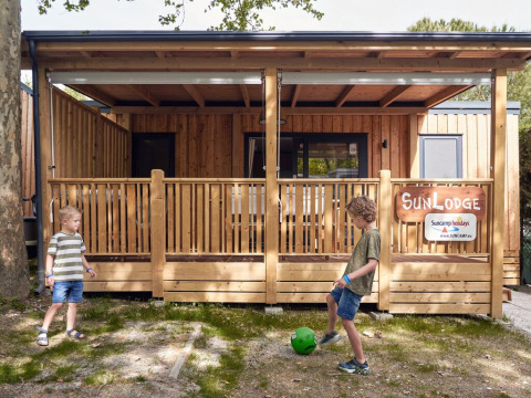 Dos niños juegan frente a una SunLodge Mobile Home en el camping Pra'delle Torri en Italia durante un día soleado.