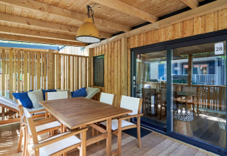 Terraza cubierta de madera con mesa de comedor y zona lounge en SunLodge Mobile Home Katsura, Italia.