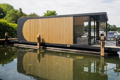 Moderne husbåd med træpaneler og glasvægge fortøjet på vandet i Lemmer, Friesland, Holland.