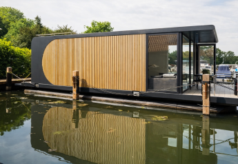 Casa flotante moderna con paneles de madera y paredes de vidrio atracada en Lemmer, Frisia, Países Bajos.