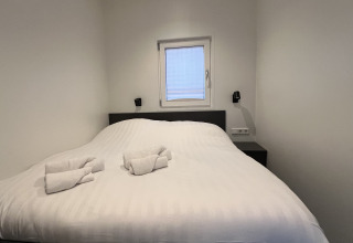 Moderne husbådssuite i Lemmer, Holland, med dobbeltseng, hvide lagner og rullede håndklæder.