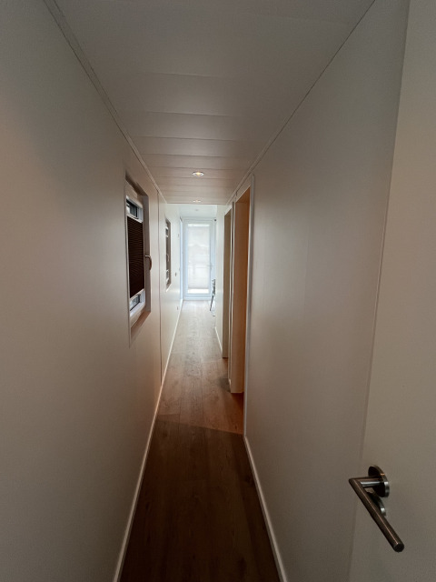 Smalt gangareal med trægulv og hvide vægge på en husbåd i Marina Lemmer, Friesland, Holland.